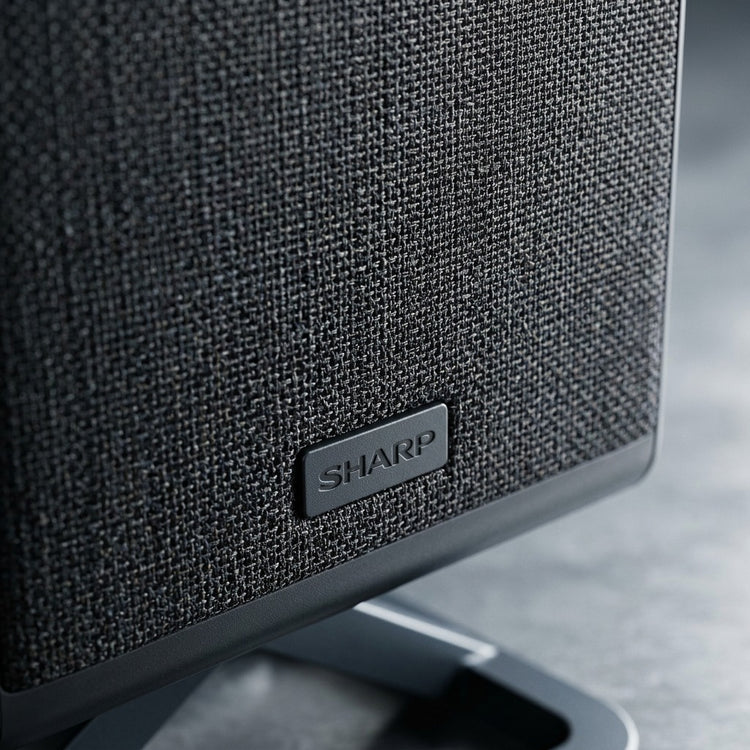 Macro detail of the Sharp HT-SPR52021-BK wireless speaker featuring premium black fabric mesh.